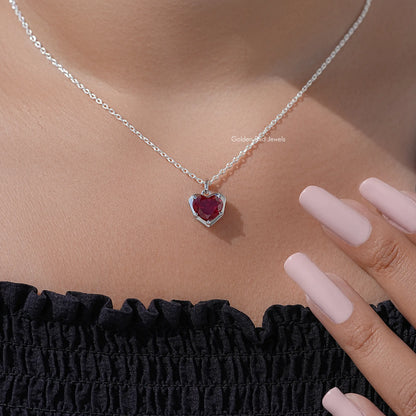 Red heart solitaire pendant necklace on silver chain, shown with hand