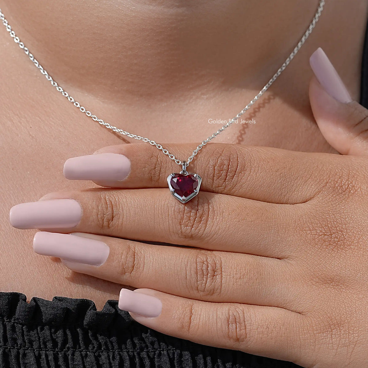 Red heart solitaire necklace pendant on silver chain resting on open palm