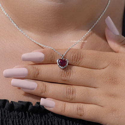 Red heart solitaire necklace pendant on silver chain resting on open palm