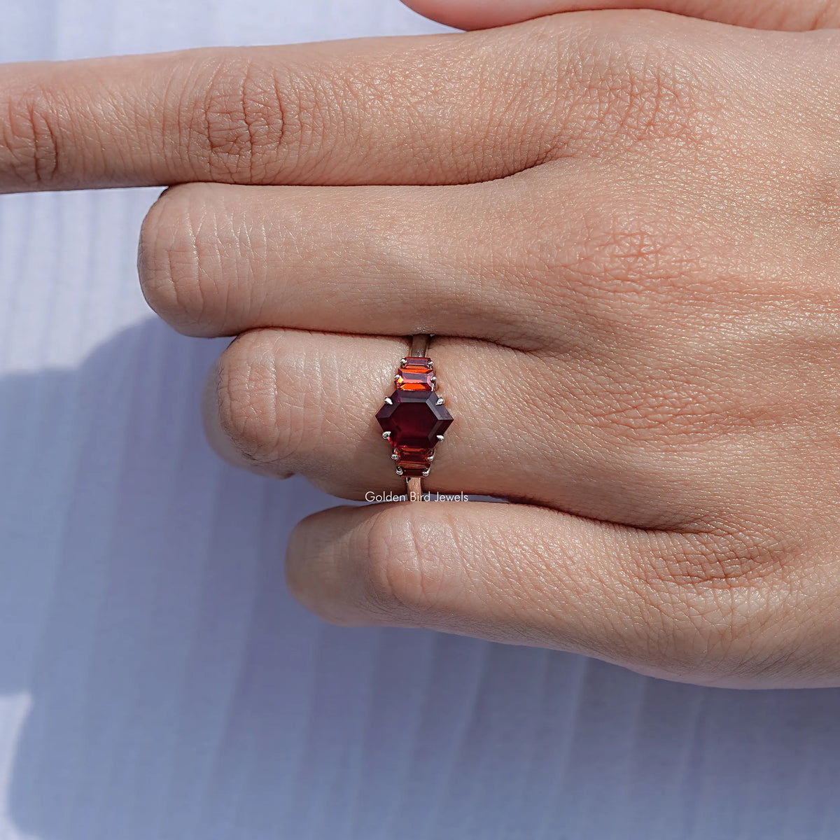 Red hexagon-cut five-stone ring viewed from side, silver-tone band