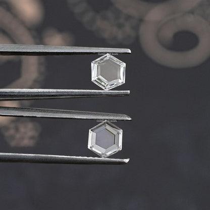 Tweezers holding a clear hexagon lab-grown diamond, faceted loose stone