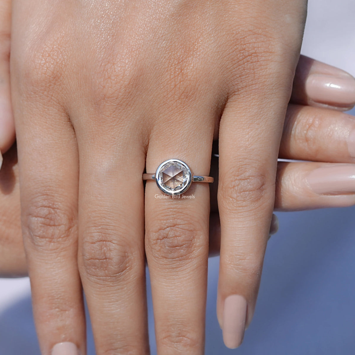 Round moissanite solitaire ring on hand, silver-tone band and prong-set center stone