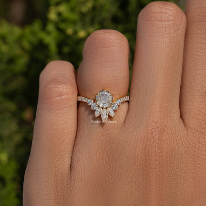 Gold-tone curved engagement ring on hand, round center stone with marquise accents