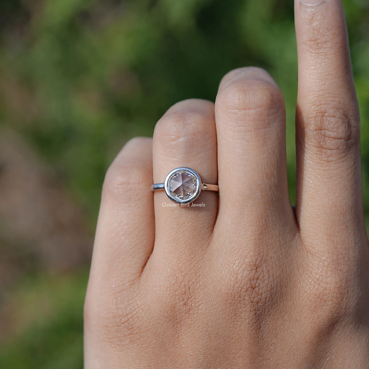 Moissanite solitaire ring on finger, round prong-set stone in a silver-tone band