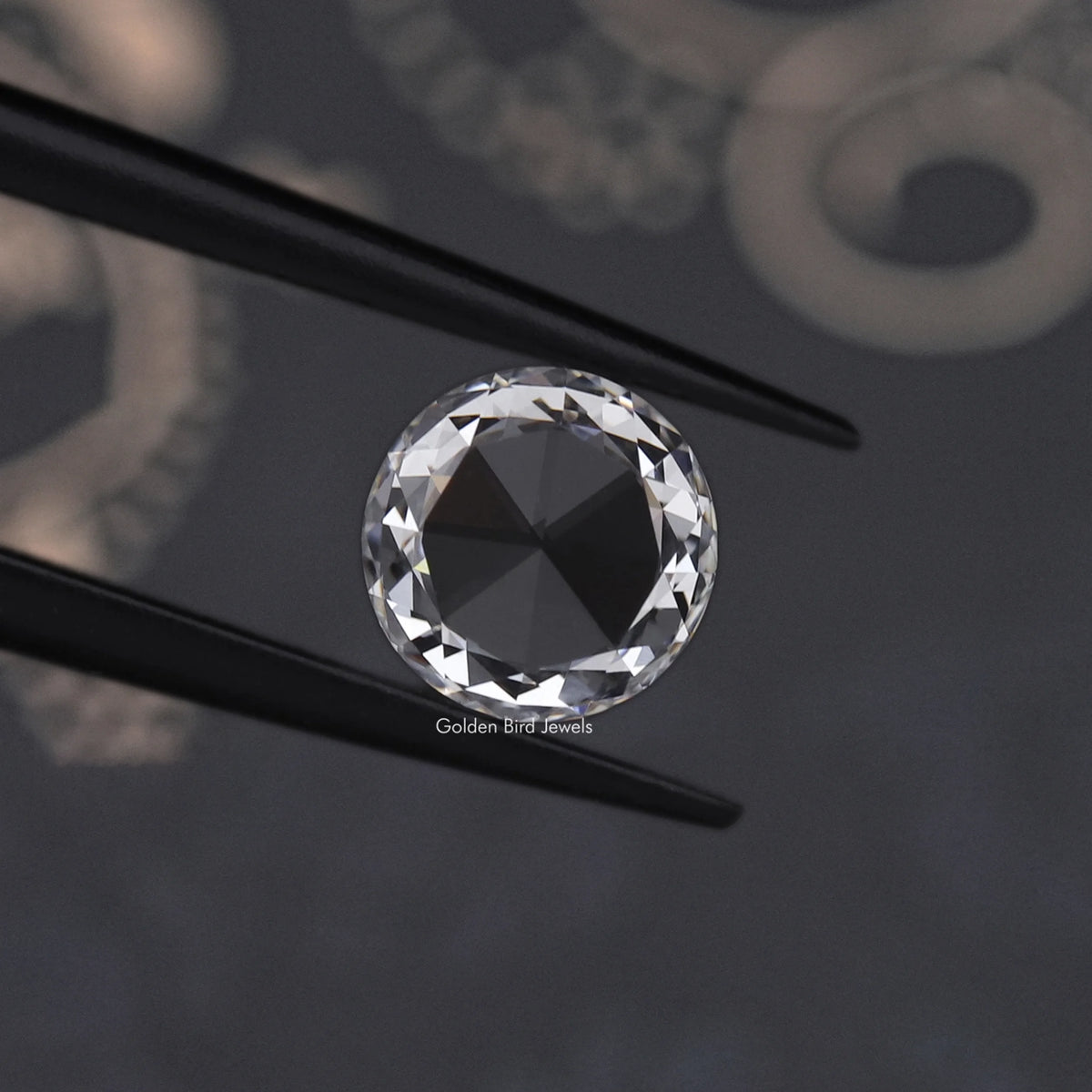 Round rose-cut lab-grown diamond close-up between two black prongs, tilted angle