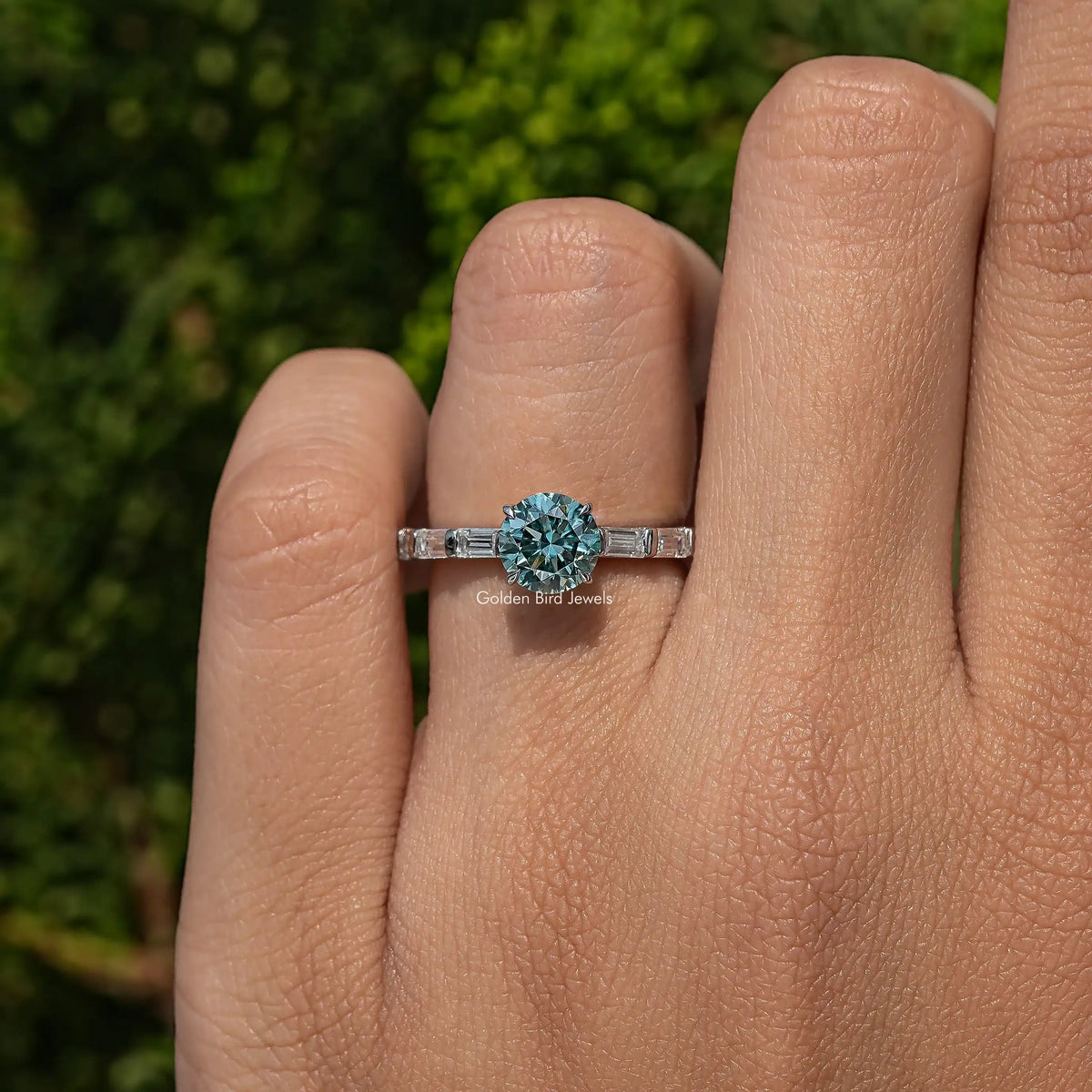 Moissanite accent ring on finger, round center stone with baguette side accents