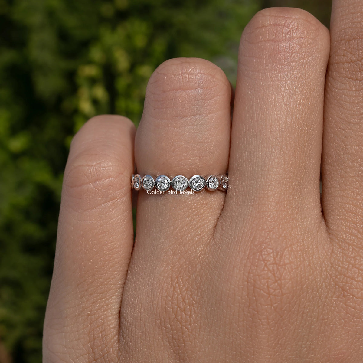 Silver-toned round bezel lab diamond wedding band with five round bezel stones, front view