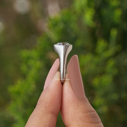 Pear-cut diamond bezel-set engagement ring in silver, top view held in fingers