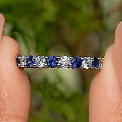 Detailed view of eternity band with alternating blue and clear bezel-set stones