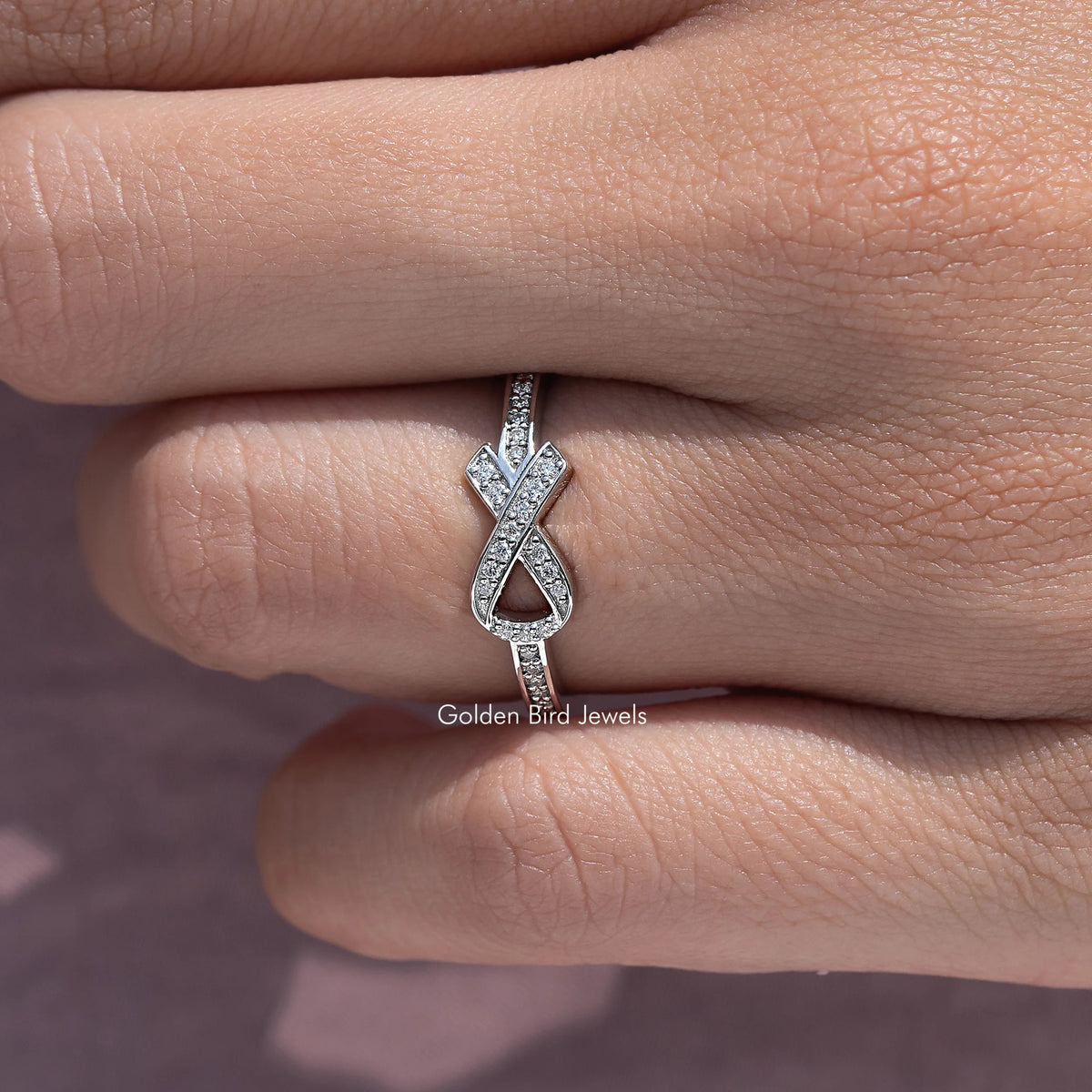 Ribbon-style moissanite ring with X ribbon motif and round-cut stones, silver tone