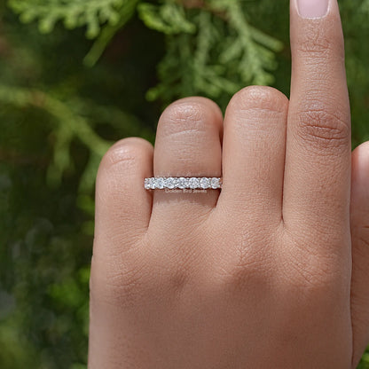 Half eternity moissanite ring with a row of clear round-cut stones, on finger