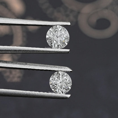 Prong-set pair of round old European diamonds, close-up between metal prongs