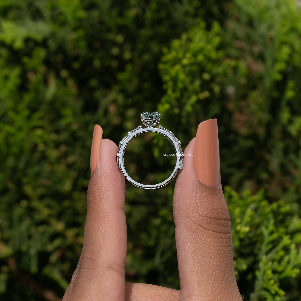 Silver moissanite ring held up, round halo-style setting and open band look