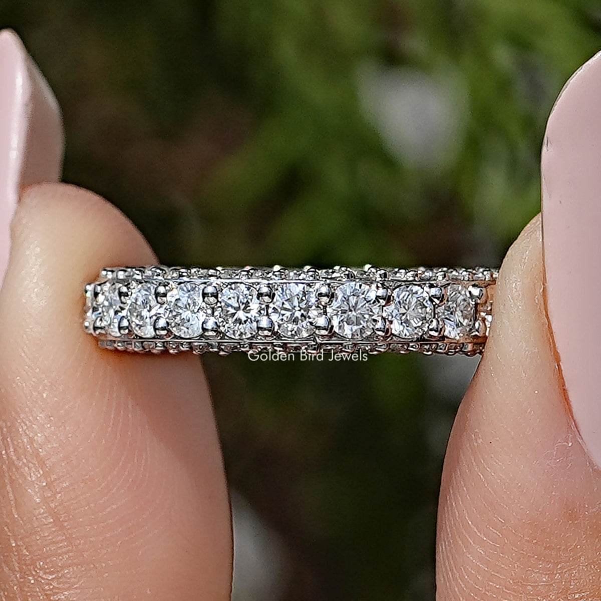 Moissanite eternity band with round pave-set stones, shown between fingers