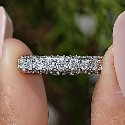 Moissanite eternity band with round pave-set stones, shown between fingers