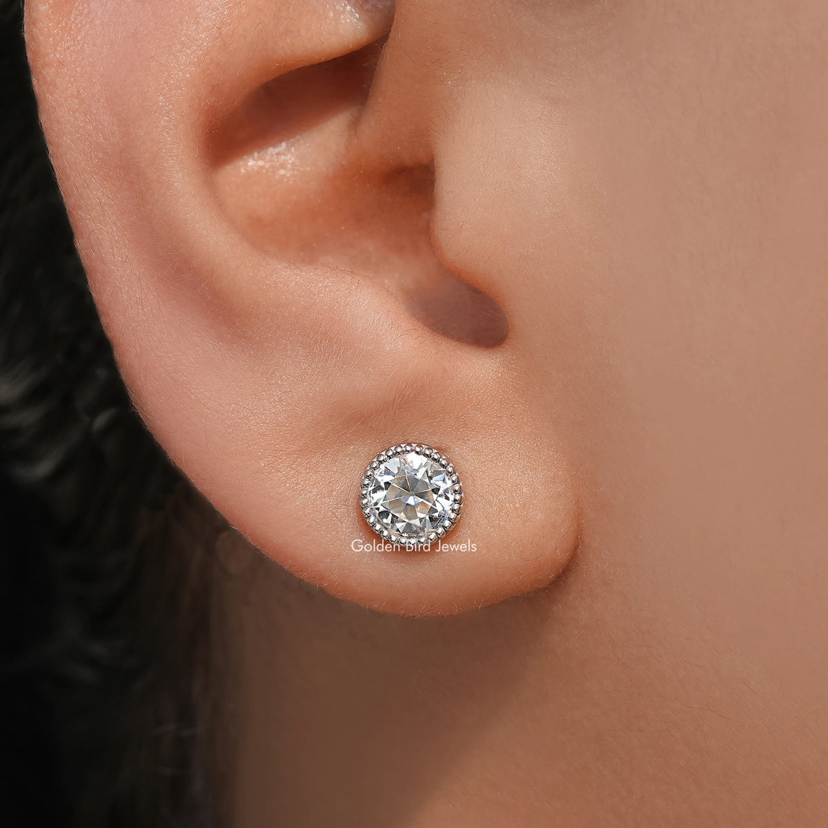 Round milgrain bezel stud earring close-up on ear with clear round center stone