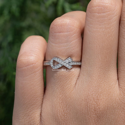 Moissanite ring with raised ribbon X centerpiece and round-cut stones on slim band, silver