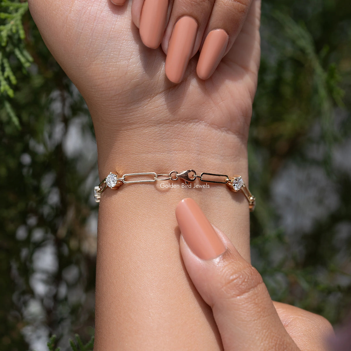 Gold-tone bracelet with round-cut stones and small link chain, worn on wrist