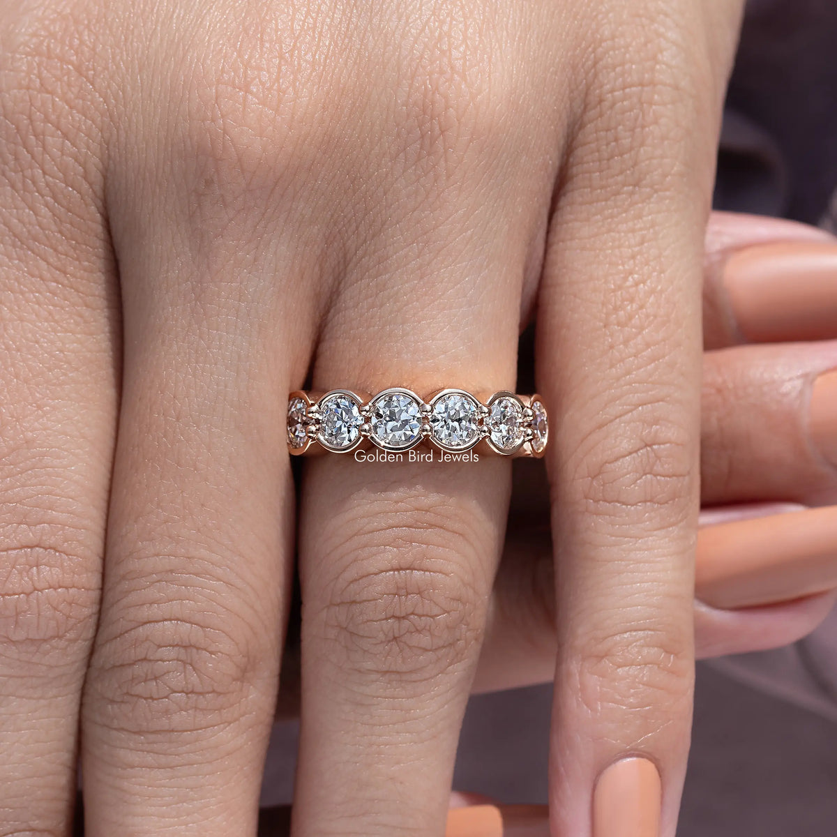 Bezel-set round diamond wedding band with three stones across the top view