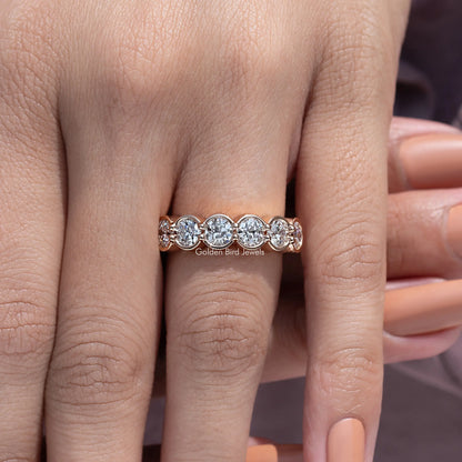 Bezel-set round diamond wedding band with three stones across the top view
