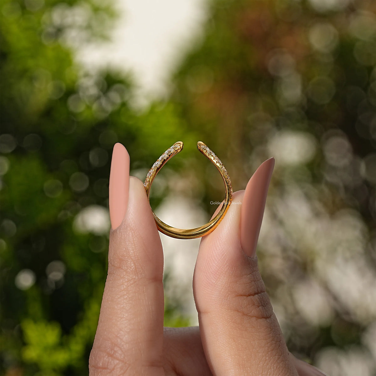 Gold open V-shape wedding band with round-cut stones, shown from front on hands