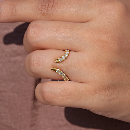 Gold open V-shape ring with round-cut stones on side, detailed on fingertips