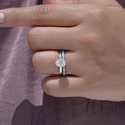 Oval-cut moissanite bridal ring set with solitaire and pavé band on finger