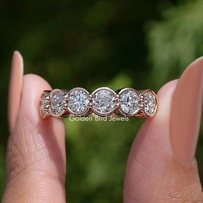 Rose-gold tone wedding band with bezel-set round diamonds in a scalloped row