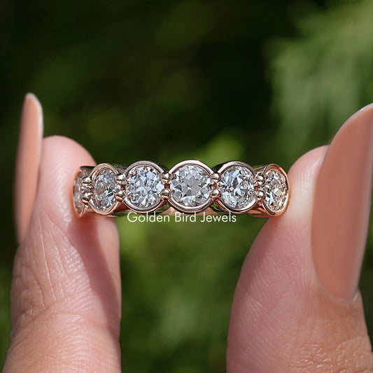 Rose-gold tone wedding band with bezel-set round diamonds in a scalloped row