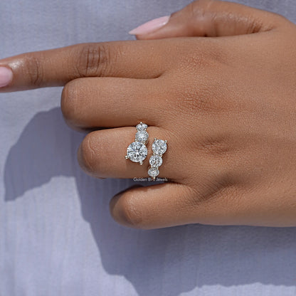 Close-up of a round-cut moissanite bypass ring with three stones on fingertip