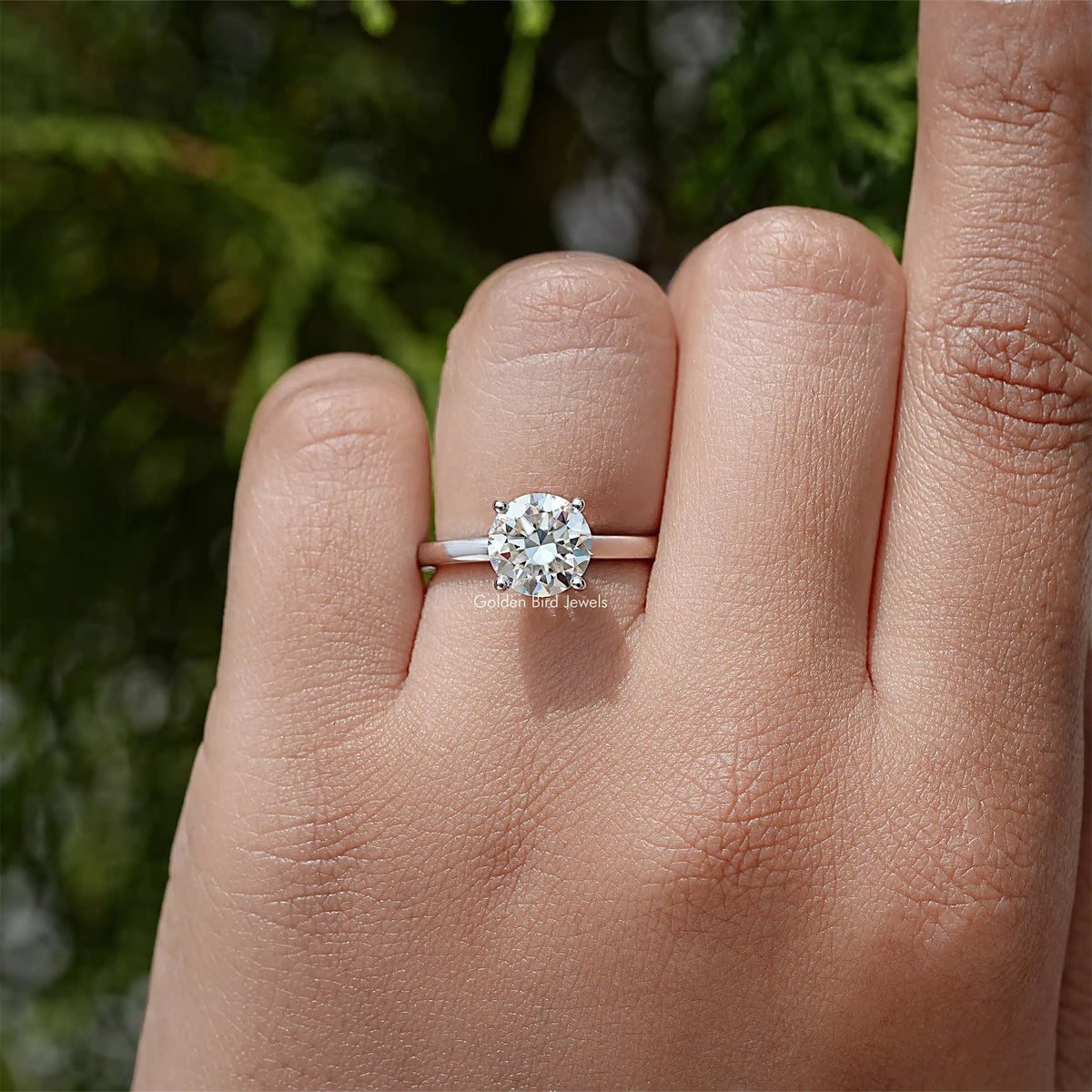 Round hidden-halo moissanite wedding ring on finger, sterling silver band