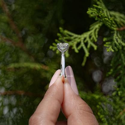 Sterling silver hidden-halo moissanite ring held between fingertips
