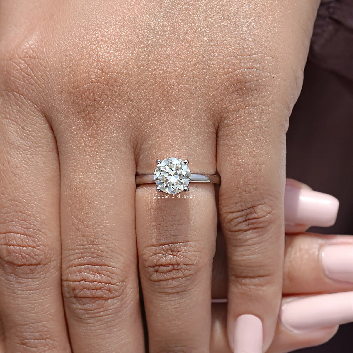 Sterling silver round moissanite wedding ring on hand, close side view