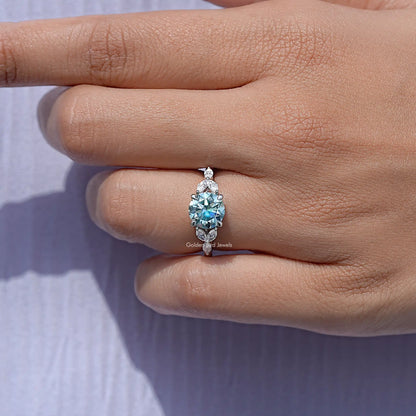 Round-cut moissanite engagement ring with round center stone, held between fingers