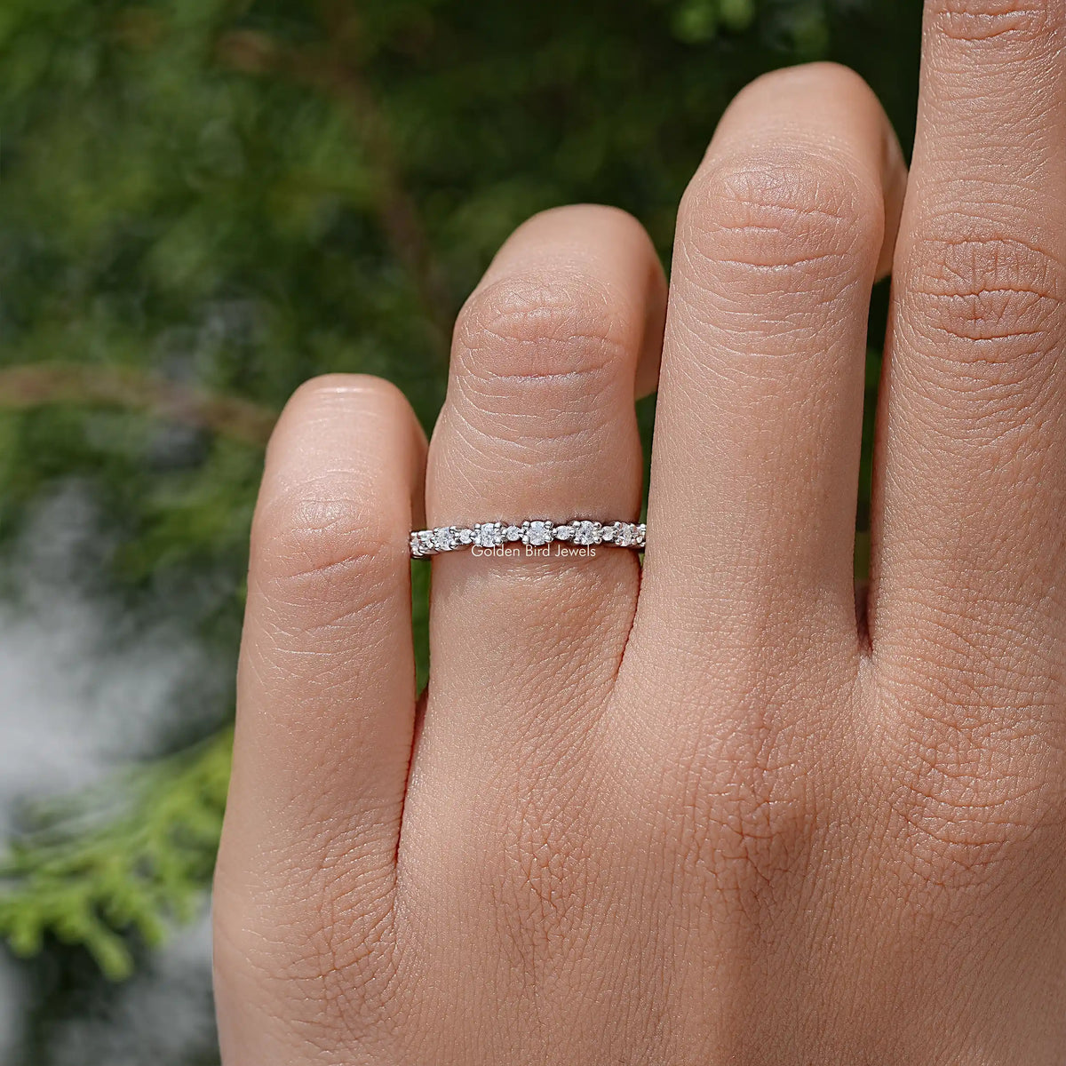 Silver eternity wedding band with round moissanite stones on the finger