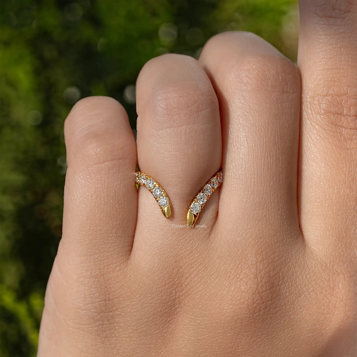 Gold open V-shape wedding band with round-cut stones, close view on stacked fingers