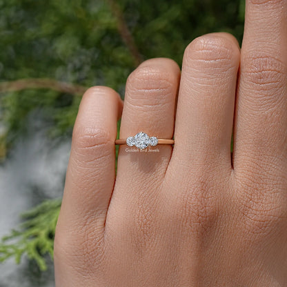 Three-stone round diamond ring on hand, center stone with two smaller side stones