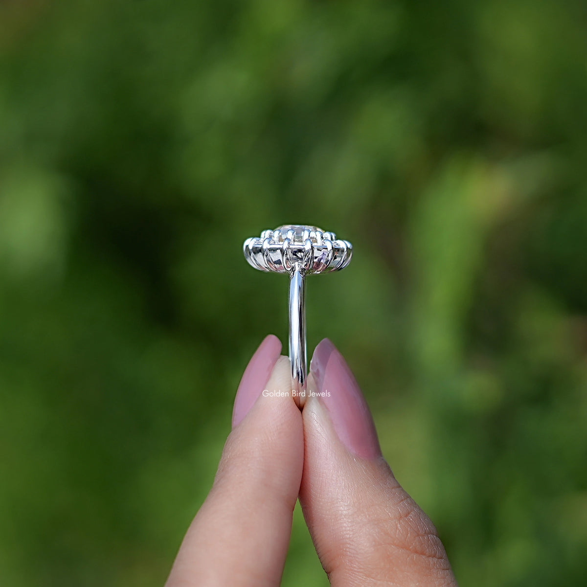 Side view of silver round halo ring with sparkling band and prongs