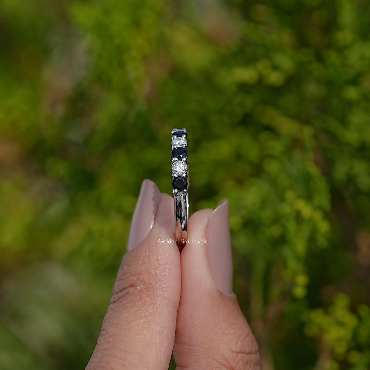 Silver eternity ring end view with stacked round dark and clear gemstones