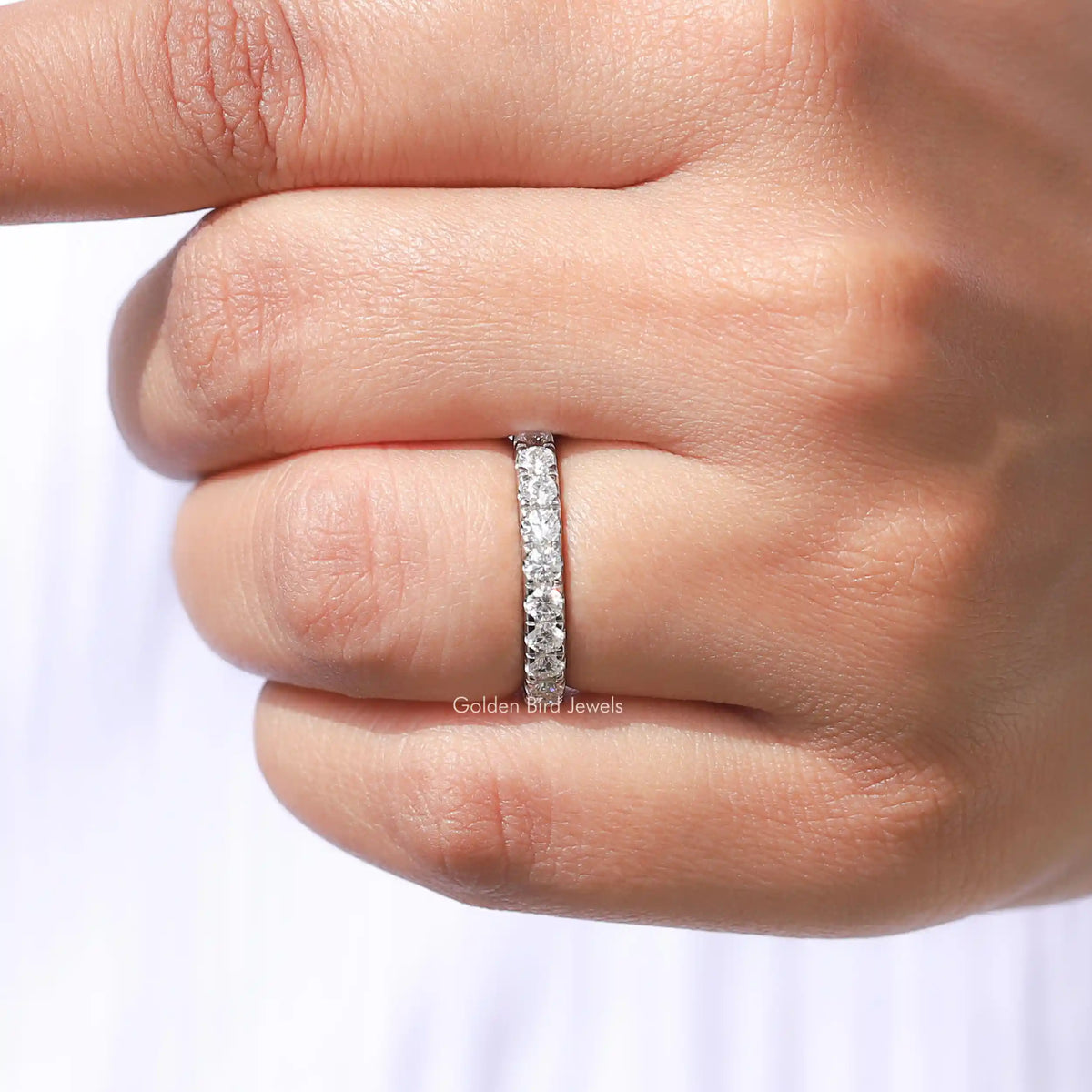 Close-up of sterling silver moissanite eternity band with prong-set round stones
