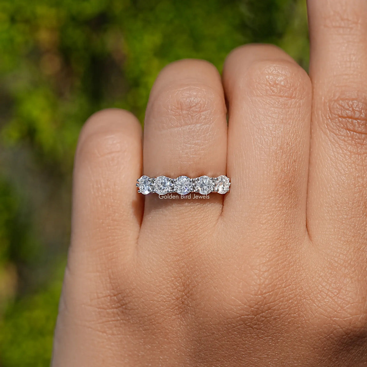Five-stone round moissanite band on finger, close-up front view in 925 sterling silver