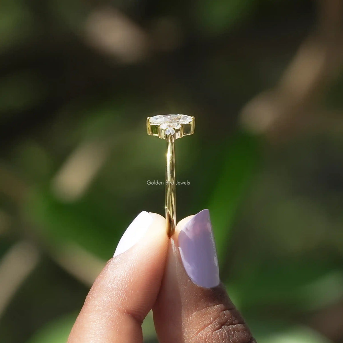 Side View of Marquise And Round Cut Engagement Ring In two fingers
