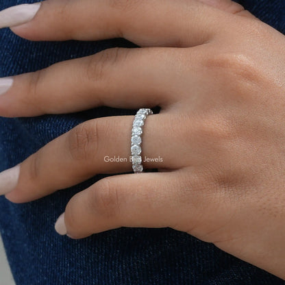 3/4 eternity moissanite band ring with sparkling round stones on a light skin hand
