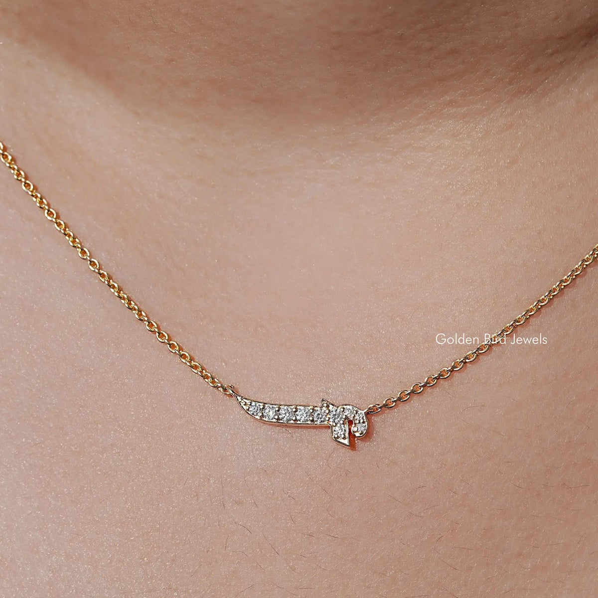 Gold-tone necklace with a small initial pendant set with round-cut stones, close-up.