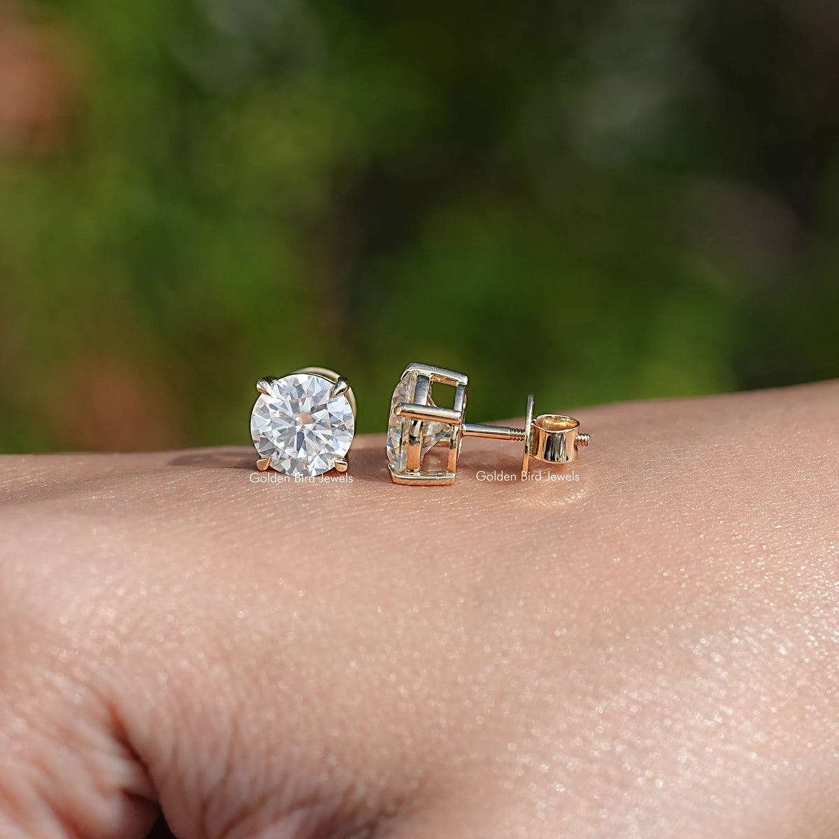 Round moissanite stud earrings with gold-tone bezel and push-back clasp, close-up