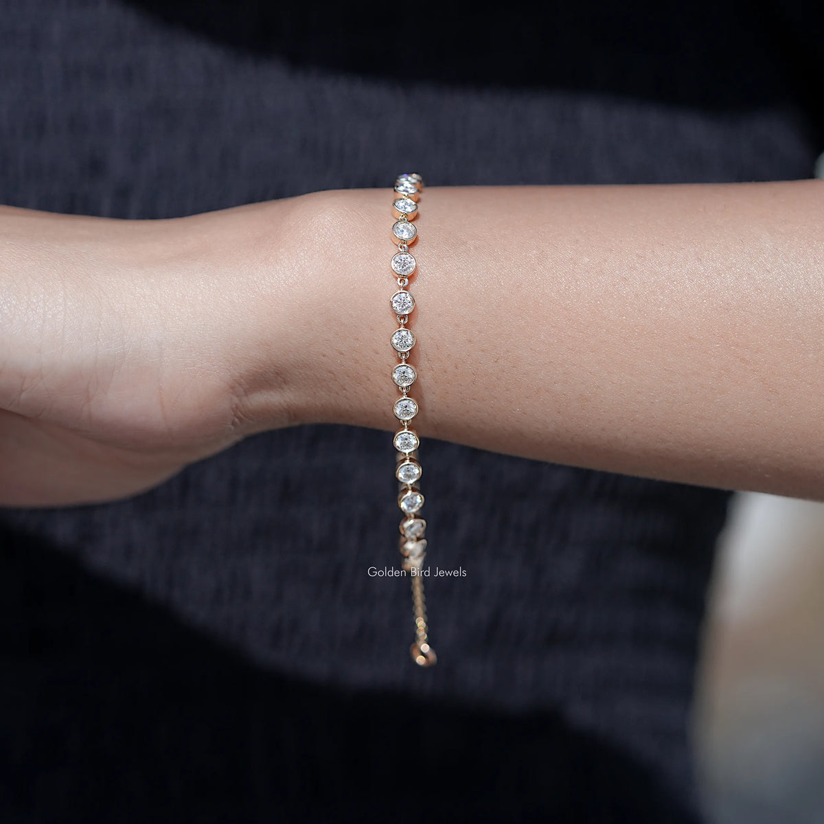 Gold-tone bracelet featuring a row of round clear gemstones on a fine chain