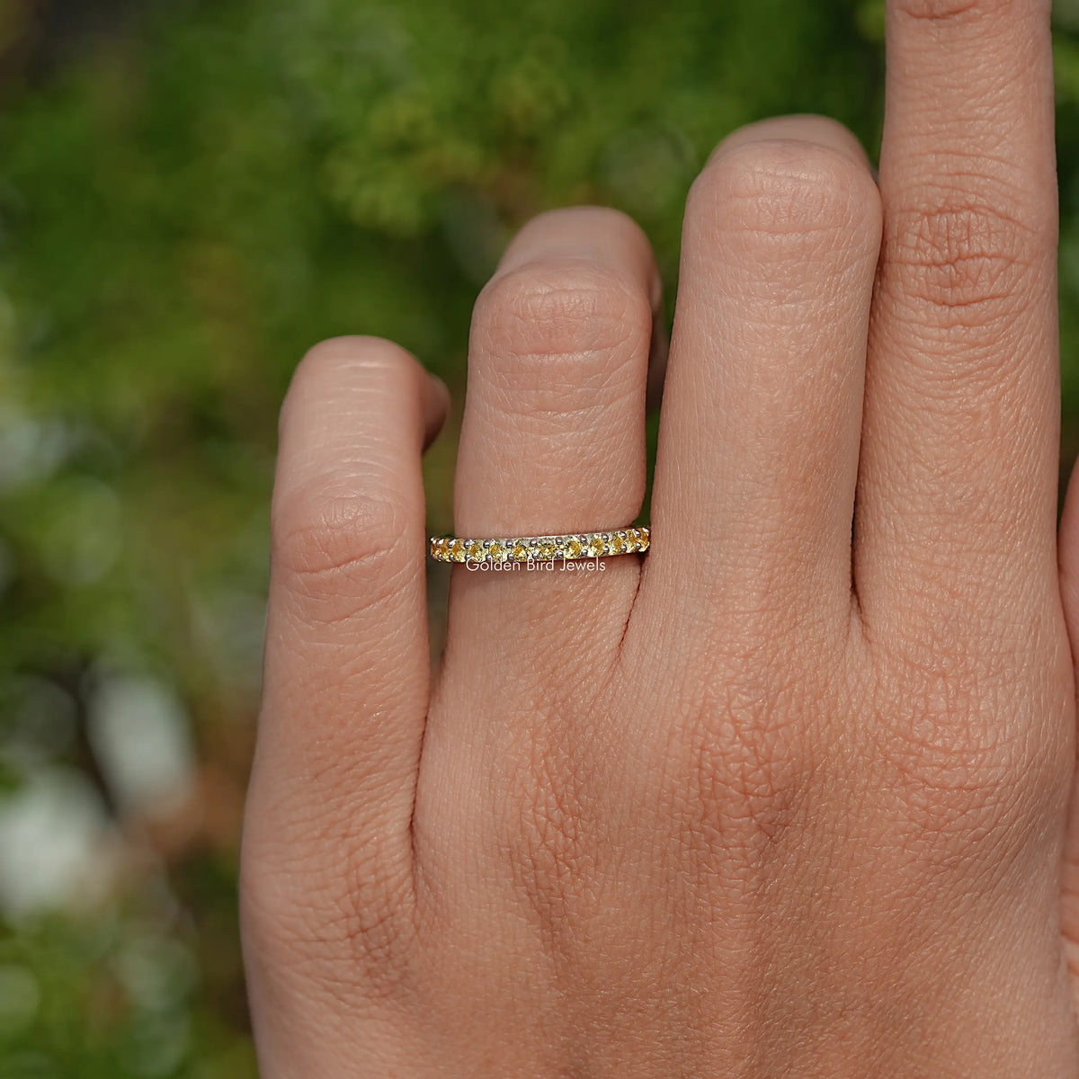 Gold-tone eternity ring with round yellow stones on finger