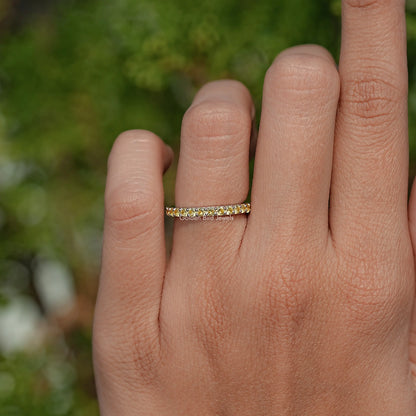 Gold-tone eternity ring with round yellow stones on finger