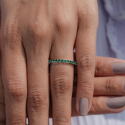 Emerald green eternity band ring close-up on fingers with round stone settings
