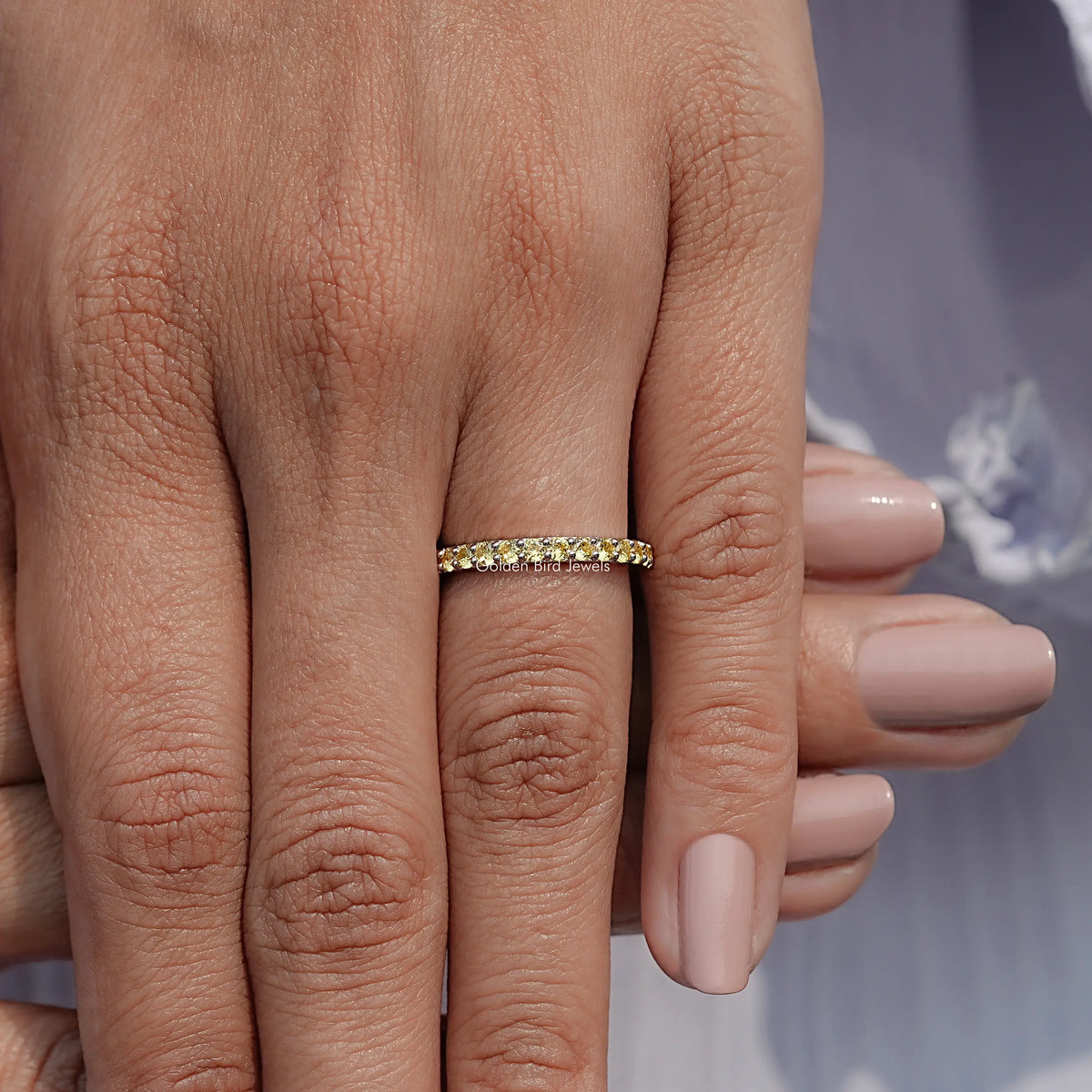 Gold-tone eternity ring with round yellow gemstones on hand, close-up